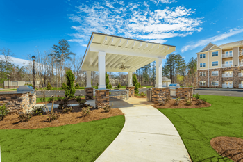A white covered walkway leads to a building with a stone pillar on each side.